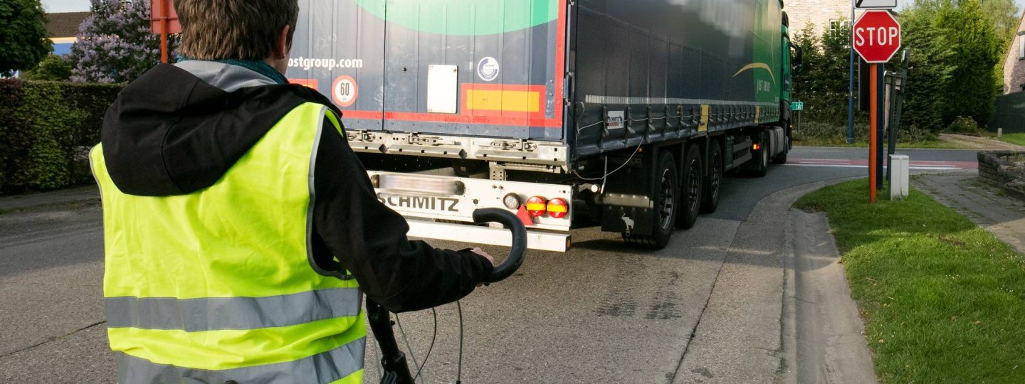 vrouw op fiets achter vrachtwagen aan kruispunt