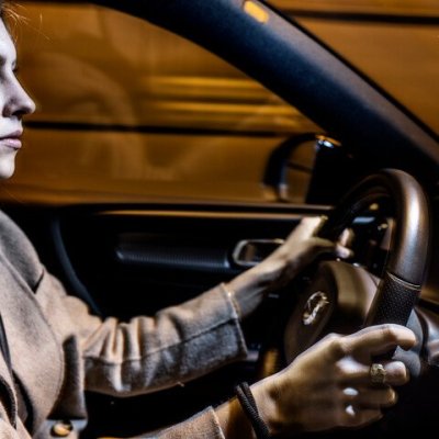 vrouw die geconcentreerd rijdt met handen aan het stuur