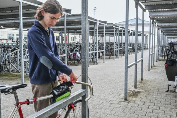 jongen die gsm wegbergt in tasje aan de koersfiets bevestigd