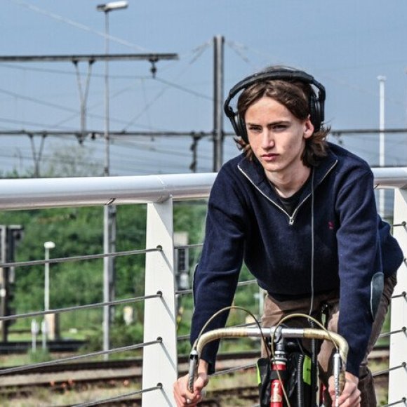 jongen op koersfiets met koptelefoon die een oor bedekt