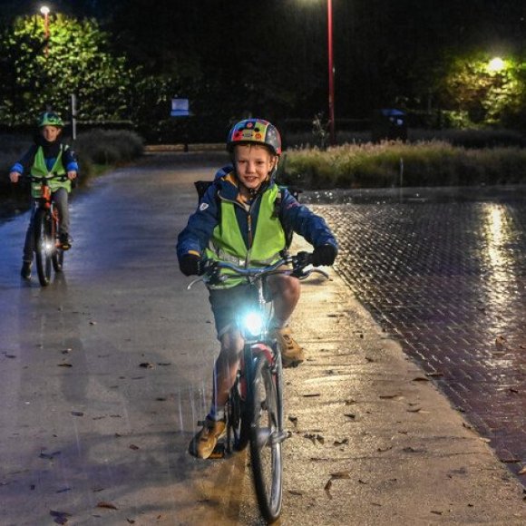 jongen op fiets in het donker, fietsverlichting brandt