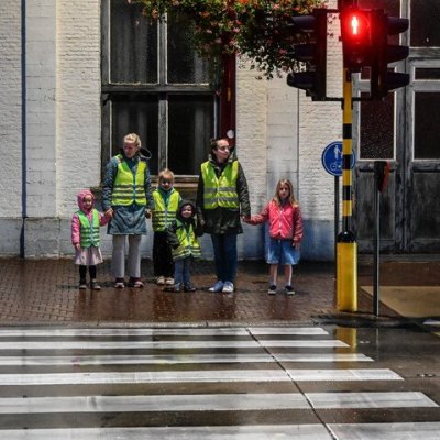 Kinderen in een fluohesje in het donker bij een zebrapad