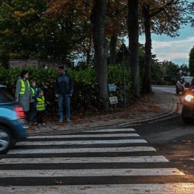 oversteken aan een zebrapad in het schemerdonker, moeder met kinderen in fluohesje