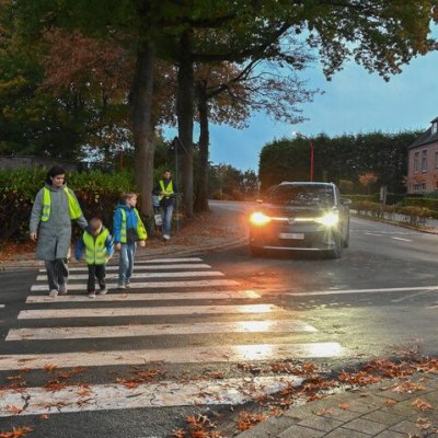 voetgangers in fluohesje oversteken op een zebrapad in het schemerdonker