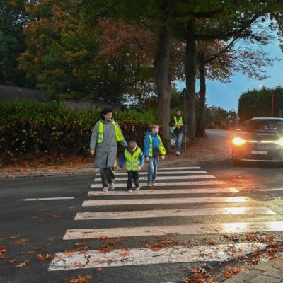 voetgangers in fluohesje oversteken op een zebrapad in het schemerdonker