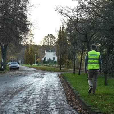 oetganger die op vehoogde berm stapt in straat zonder voetpad