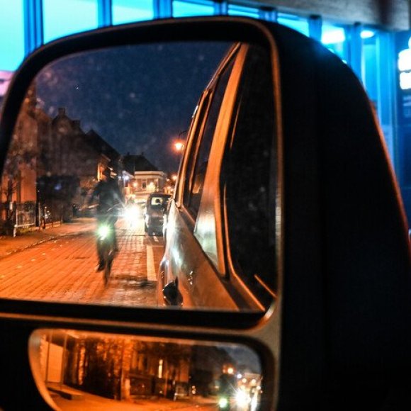 Fietsers in het donkbaar, zichtbaar door een autospiegel